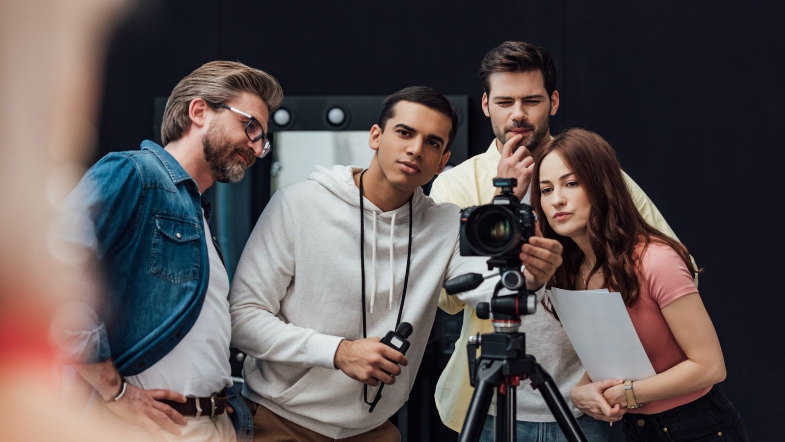selective focus of happy art director near coworkers and digital camera in photo studio