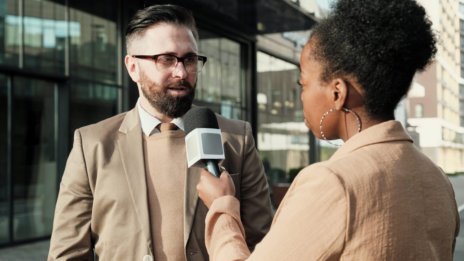 African woman with microphone interviewing the man while they standing in the city